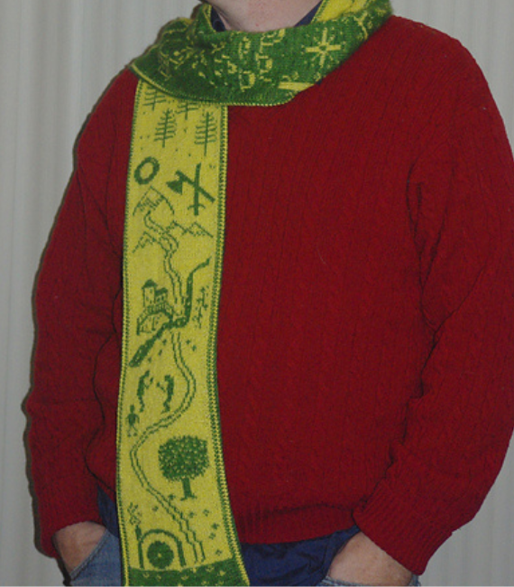 Image of a man from the neck down wearing a red sweater and a bright green scarf in two tones that features iconic scenes from The Hobbit by J.R.R. Tolkien