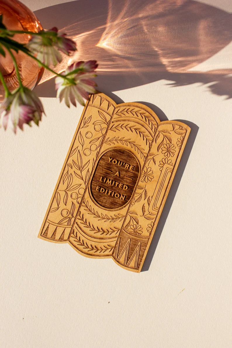 Laser engraved, book shaped wooden card that says "you're a limited edition" with floral print