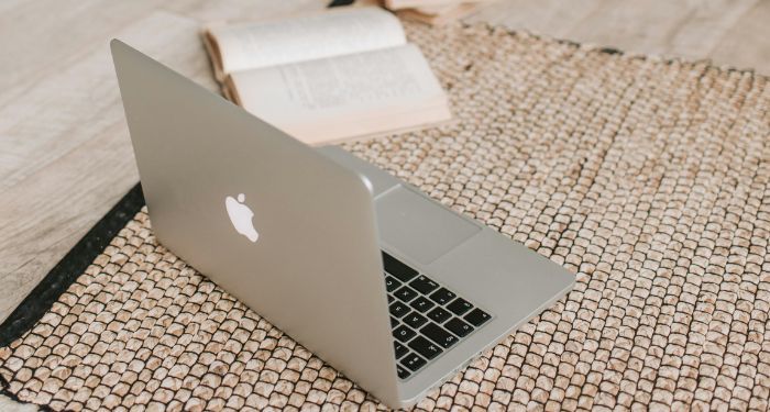 open laptop and book on a beige rug