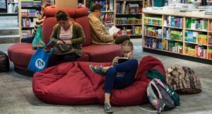 people in a bookstore reading books on red couches and cushions