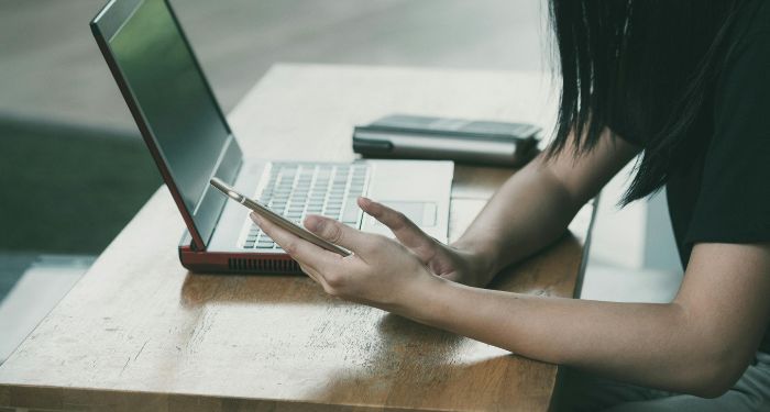 person looking at their phone with laptop open