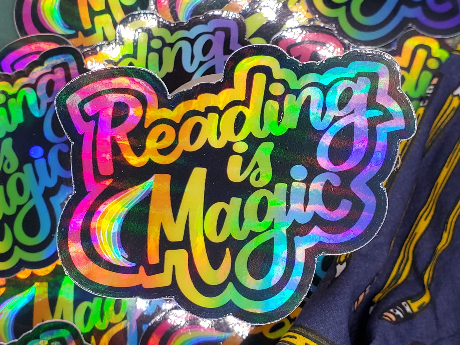 Image of a holographic sticker that says "reading is magic."