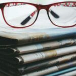 red eyeglasses on a stack of newspapers