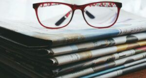 red eyeglasses on a stack of newspapers