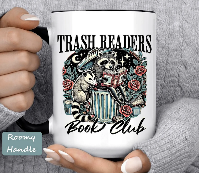 a mug with an illustration of a raccoon and an opposum on a trashcan reading a book with text saying Trash Readers Book Club