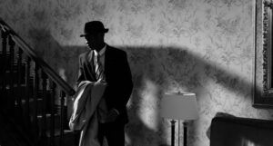 a black and white photo of a Black man in a suit with a hat