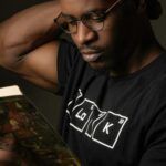 a brown-skinned Black man reading a book