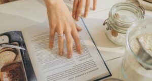 a fair-skinned hand holding open a cookbook