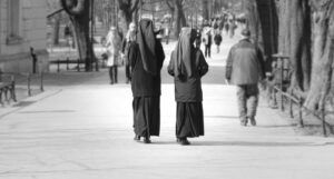 black and white picture of nuns walking on a sidewalk