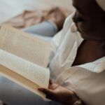 brown-skinned Black woman with a head wrap reading a book