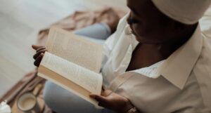 brown-skinned Black woman with a head wrap reading a book