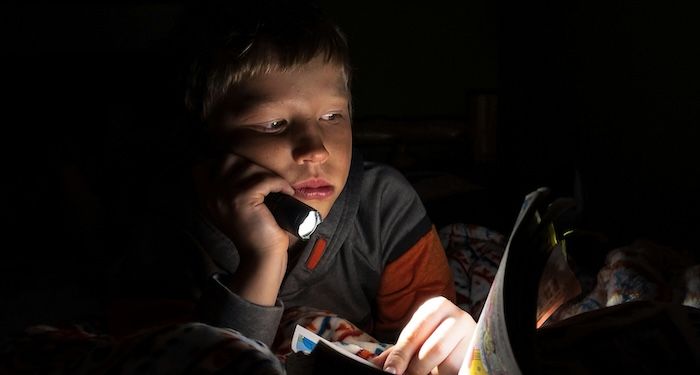 kid reading comics by flashlight.jpg.optimal