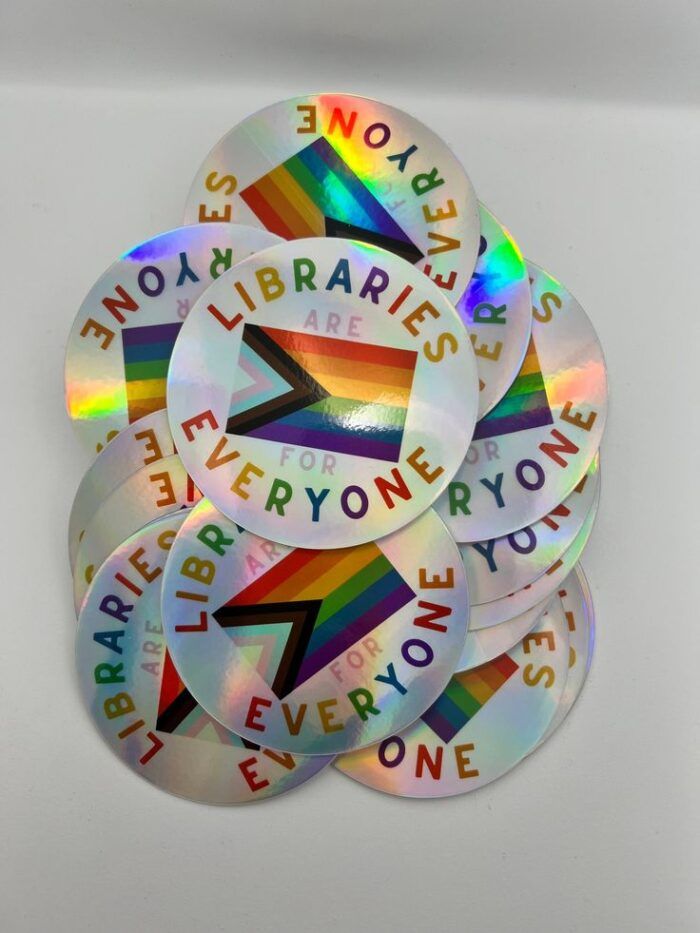 circular holographic sticker that says libraries are for everyone pride flag 