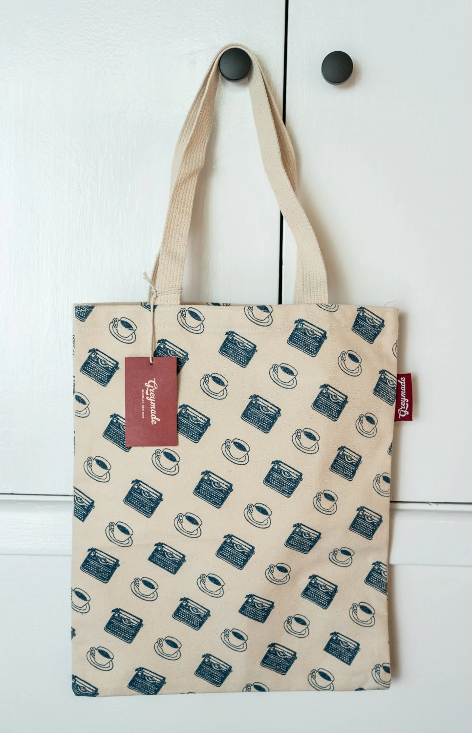 Image of a tote bag with a pattern featuring coffee cups and typewriters