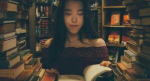 woman reading a book while surrounded by books in a bookstore
