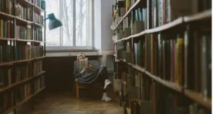 woman reading on a chair in the aisle of a bookstore or library feature