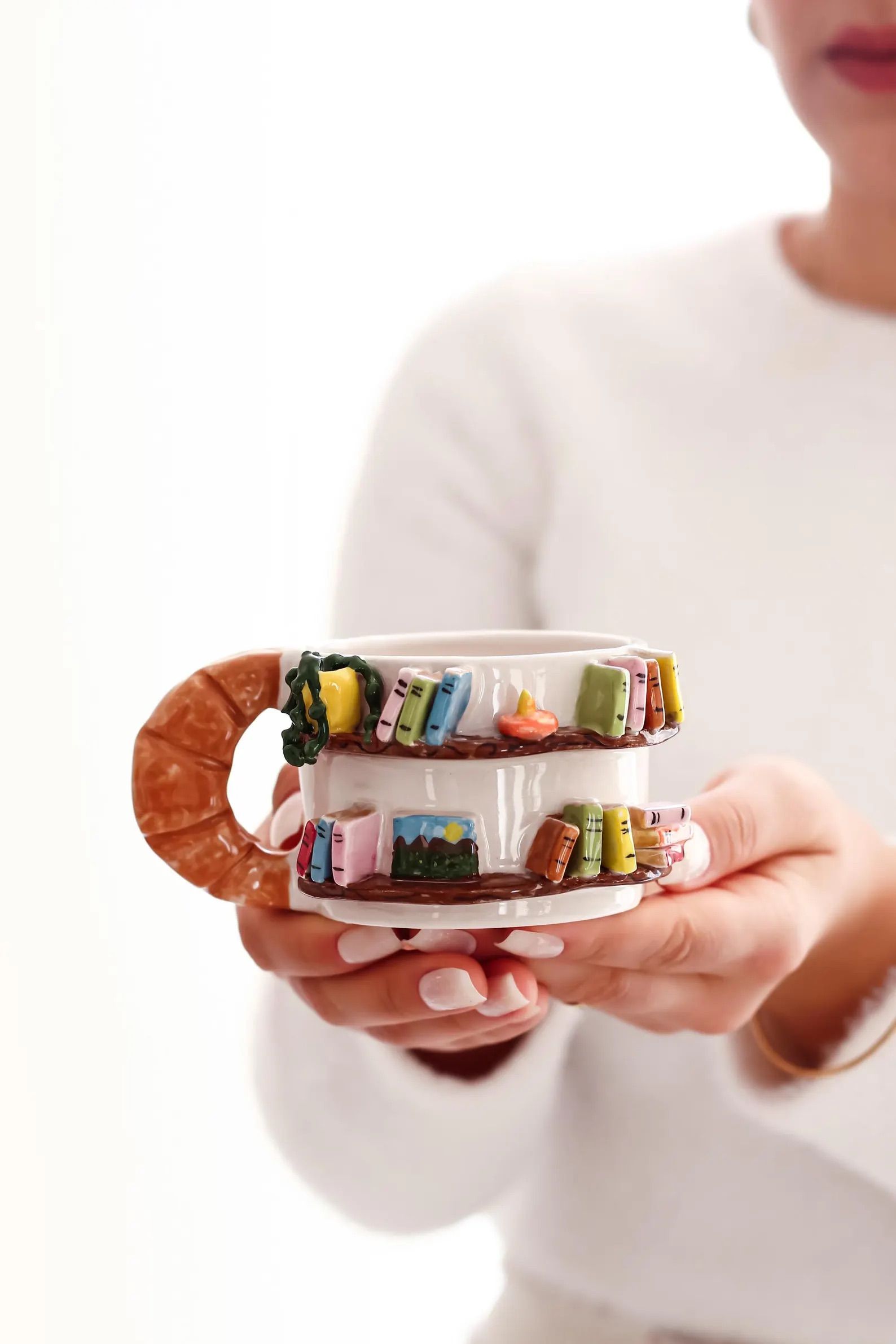 Library Bookshelf Mug in the hand of a person in a white shirt.