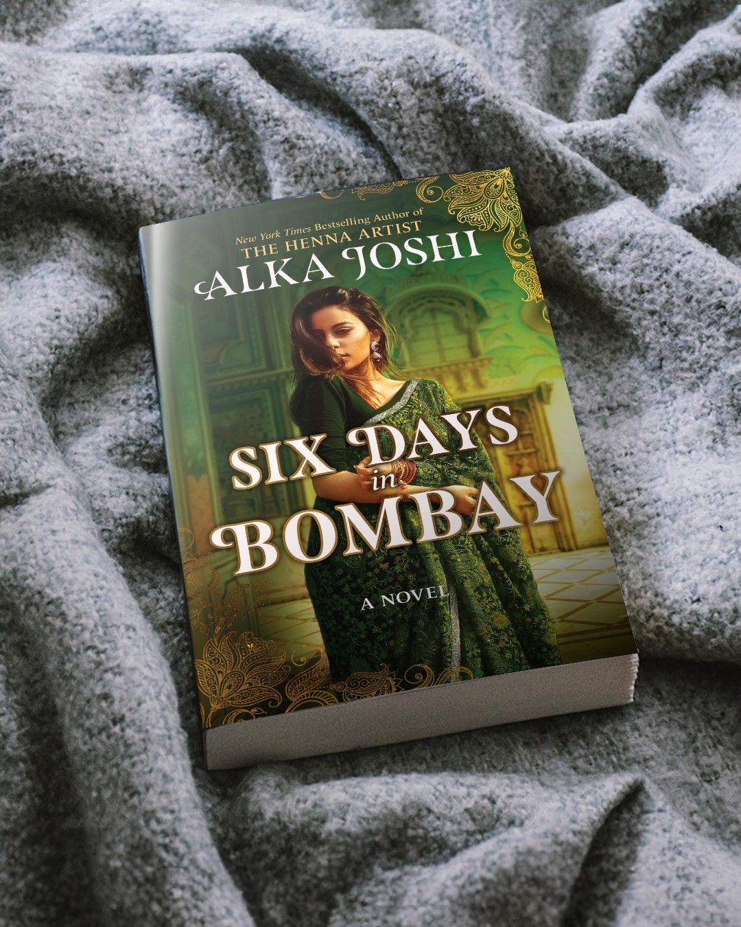 Cover of book, Six Days in Bombay by Alka Joshi, sitting on a grey blanket. 