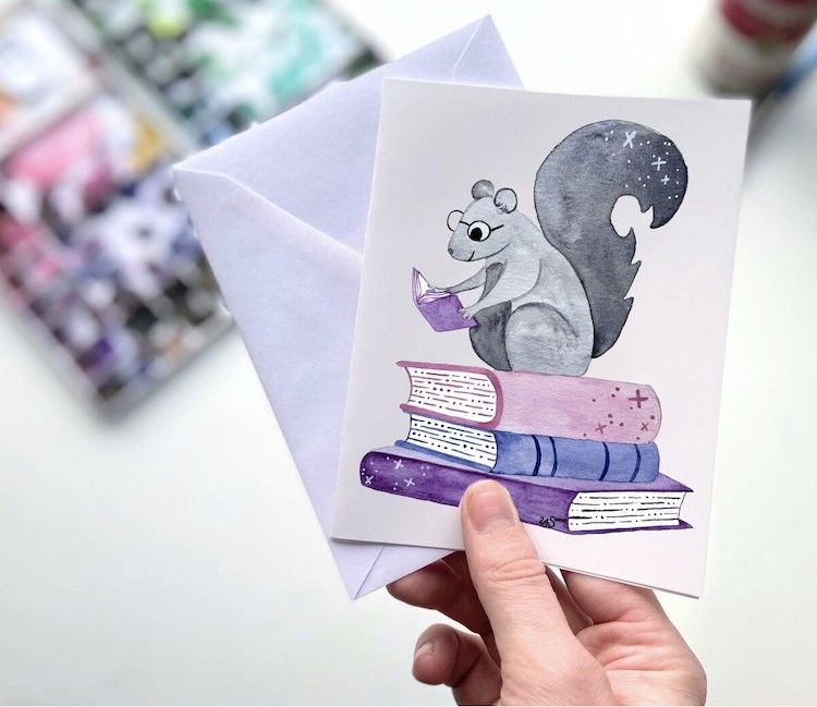 a greeting card with an illustration of a squirrel on a stack of books reading
