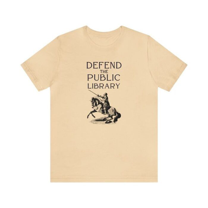 ivory short sleeve tshirt with a vintage image of a knight on a horse and text reading Defend the Public Library