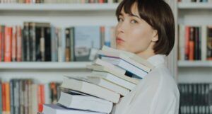 fair skinned Asian woman with a bob holding a stack of books