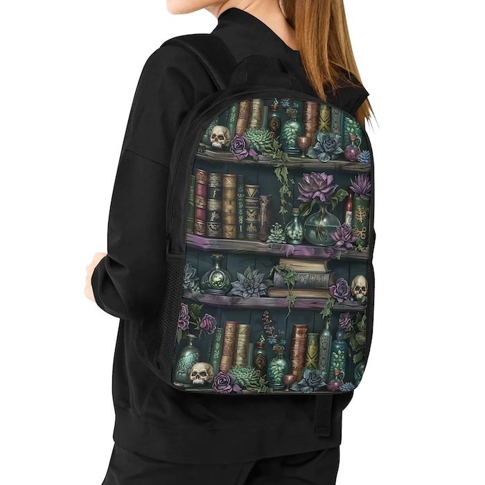 person in a black hoodie wearing a laptop backpack in a dark moody print of books, plants, and skulls on on shelves 