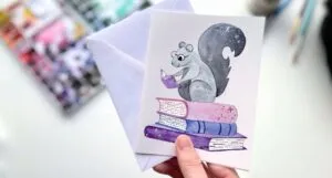 a greeting card with an illustration of a squirrel on a stack of books reading