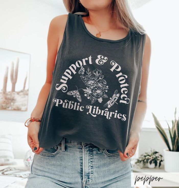 a boxy, dark blue tank top with an image of an open book, flowers, and moths and text that reads "support and protect public libraries"