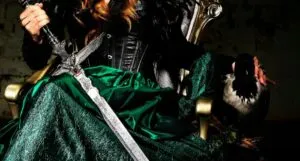 sword held by hand and crossed against green shiny skirt