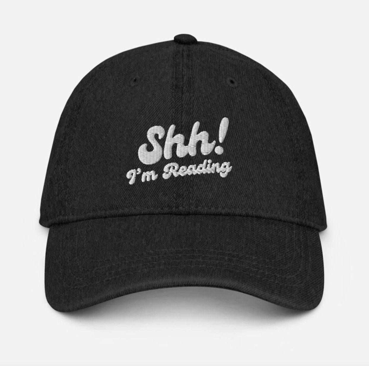 Image of a black denim baseball cap embroidered with white text "Shh! I'm reading"