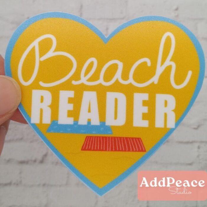 image of a large yellow heart with the white words "Beach Reader" and colorful beach towels underneath