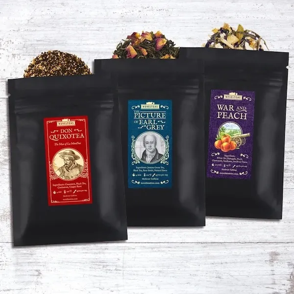 three resealable black pouches of loose leaf tea with labels for each blend: Don Quixotea, Picture of Earl Grey, and War and Peach