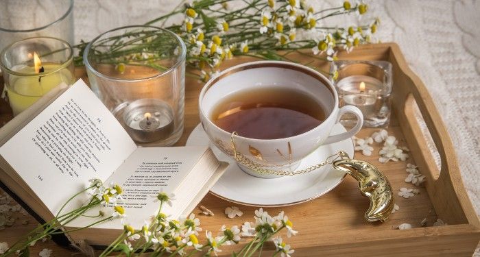 a book surrounded by flowers, candles, and a teacup