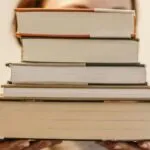 fair-skinned person holding a stack of books
