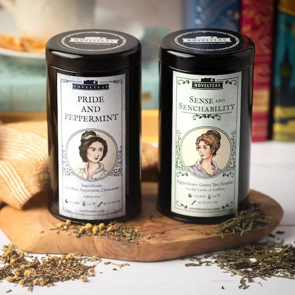 two black cylinder tins of Jane Austen-themed loose leaf tea. One is Pride and Peppermint, the other Sense and Senchability