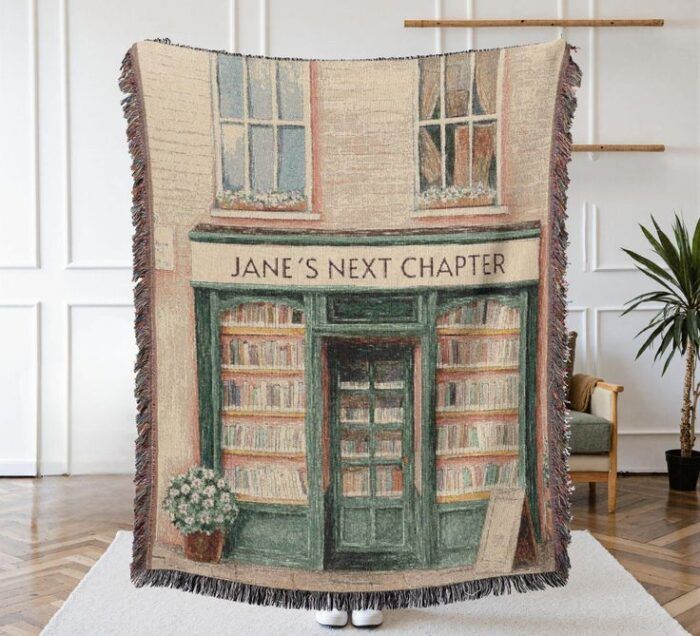 image of a woven tapestry showing the facade of a bookstore with the words "jane's next chapter" over the door