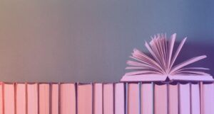 open book on top of books in a row with spines faced away and pink gradient overlay