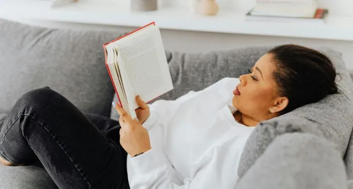 brown-skinned Black woman sitting on a couch and reading