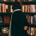 a person looking at books on a shelf