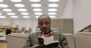 brown-skinned Black man reading a book in a library