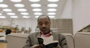 brown-skinned Black man reading a book in a library