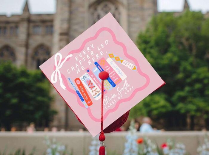 pink mortarboard topper with books, feminine styling, and the words "every chapter led me here"