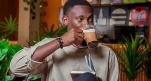a Black man sipping coffee while reading a book