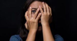 Image of a person covering their eyes and looking scared