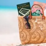 a tote bag on the beach with two fantasy covers sticking out