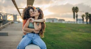 two women embracing and kissing outdoors