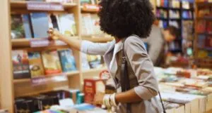 a black woman taking a book off the shelf at a book store