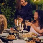 a group of femme friends drinking wine at a dinner table outside