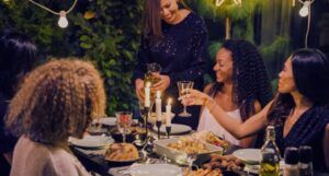 a group of femme friends drinking wine at a dinner table outside