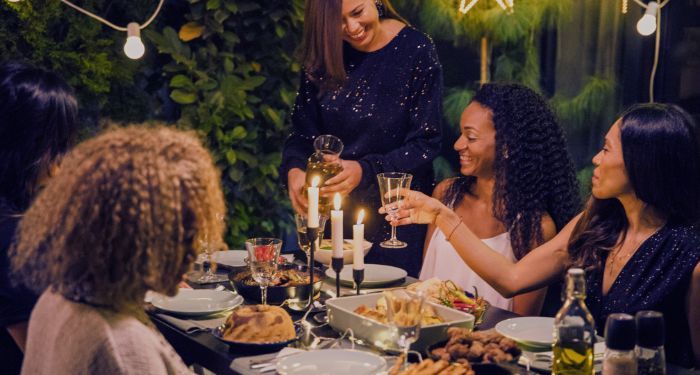 a group of femme friends drinking wine at a dinner table outside.jpg.optimal